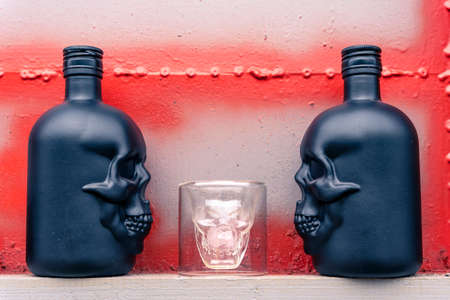 glass gin bottles in the shape of a human skull and a glass stackの写真素材