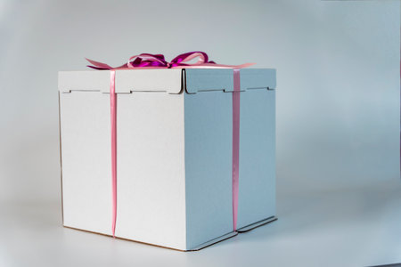 large white gift box tied with a red ribbon on a white backgroundの写真素材