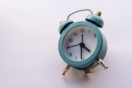 small blue alarm clock in vintage style on a white background