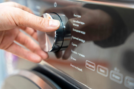 womans hand selects the washing mode with a round selector