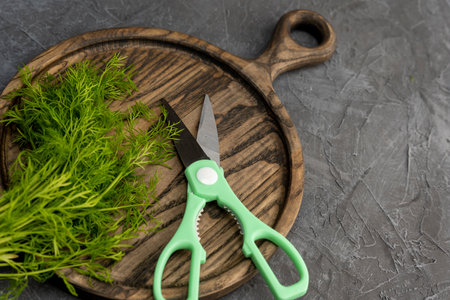 kitchen scissors cutting dill in the kitchen on a cutting boardの写真素材