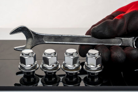 Shiny new wheel nuts and a wrench in the hand of a car mechanicの写真素材