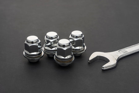 Shiny new wheel nuts and wrench on a dark background