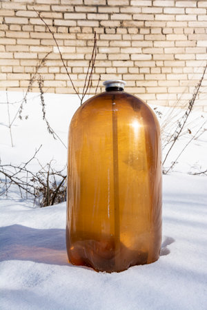 large dark plastic bottle of juice or beer in the snowの写真素材