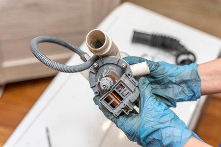 a broken old washing machine water pump in the hands of repairman
