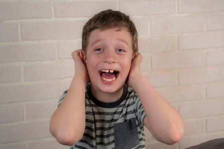 boy covers his ears with his hands and laughs