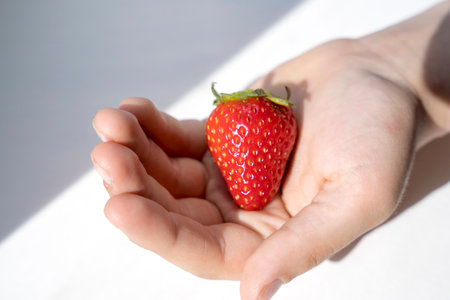 Delicious ripe juicy strawberry berry in a childs palmの写真素材