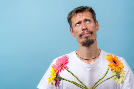 Portrait of a cute Caucasian thoughtful guy with a bouquet of flowers