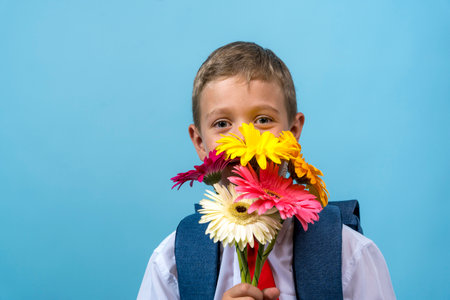 first grader with a backpack holds a bouquet of flowersの写真素材