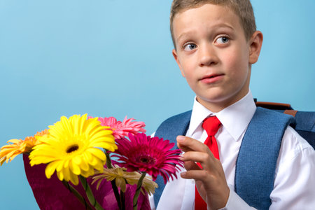 first grader with a backpack holds a bouquet of flowersの写真素材