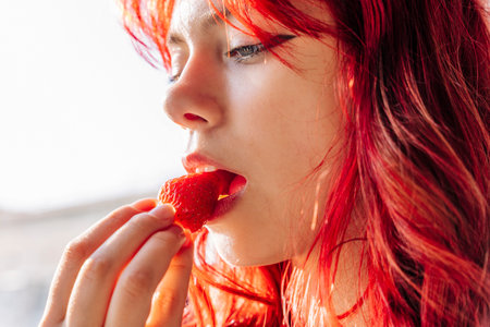 girl with red hair eats delicious ripe strawberriesの写真素材