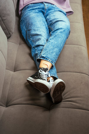 legs of a teenage girl dressed in blue jeans and new youth sneakersの写真素材
