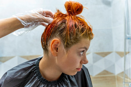 Profile of a pretty teenage girl coloring her hair red.の写真素材