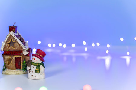 A snowman near a fabulous winter house on a blue backgroundの写真素材