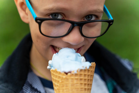boy eats ice cream in a waffle cone on the street in the park