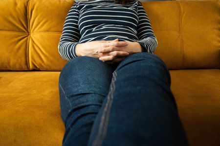 woman sits on the sofa with her legs stretched forward and her fingers crossedの写真素材