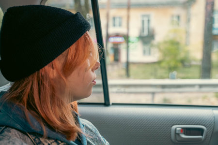 pretty girl with pink hair in a black knitted hat in the back seat of a car