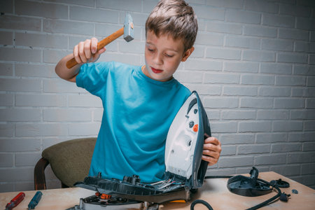 boy repairs an electric iron. a funny master repairs an electric ironの写真素材
