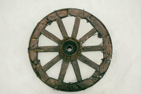 A close-up of a weathered vintage wooden wheel from an old cart, showing intricate details and aged wood, making it a perfect addition to rustic country decor or as a unique photography prop.の写真素材