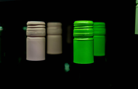 bottles of wine on the store shelf. Green and pink bottle caps with alcoholic beverages. buying wine for the holidayの写真素材
