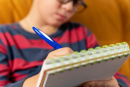 boy concentrating on drawing in his notebook in a moment of creative inspirationの写真素材