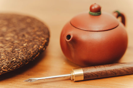 teapot made of Yixing clay. Pressed disc of black Pu-erh tea and tea knife awl
