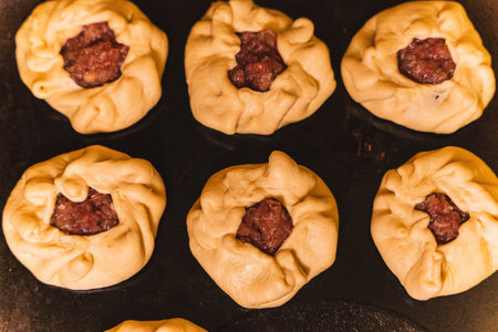 Raw belyashi with meat, popular russian pastries, ready for baking on a trayの写真素材