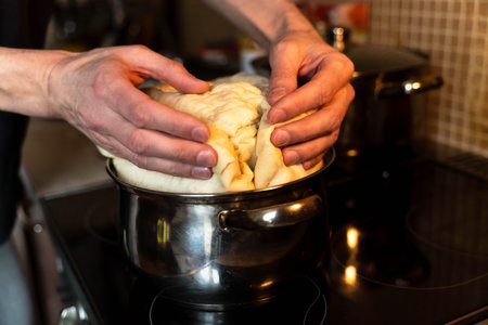 Professional chef kneading sourdough on stove for baking bread
