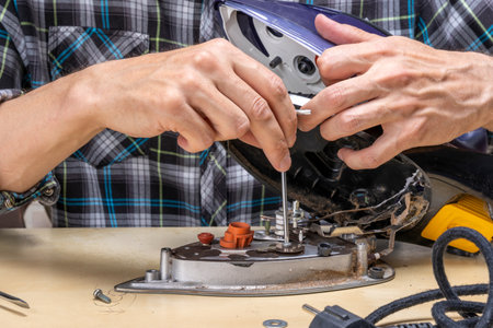 master repairs the iron in the workshop on the table using toolsの写真素材