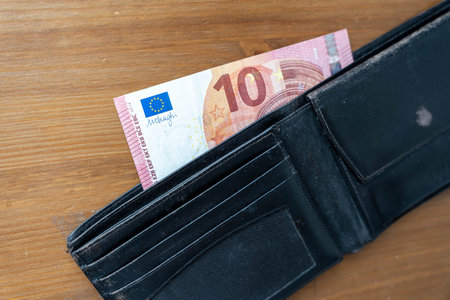 A wallet open with various bills sticking out of it, showcasing cash peeking from the wallets...