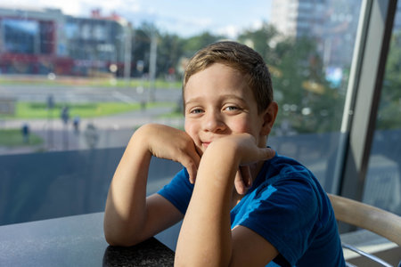 enchanting portrait of a delightful young Caucasian boy sitting in a cozy cafeの写真素材