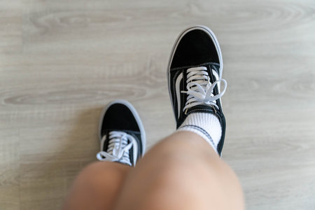 A person standing with black and white shoes on their feet.
