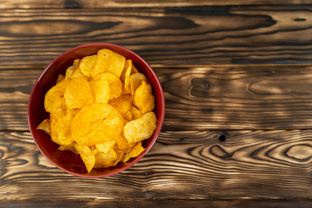 potato chips in a bowl on a wooden table, unhealthy food. top view, copy space