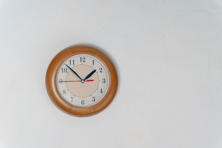 Clock Hanging on Wall in Room. time at 1 hour and 50 minutes. white wall. Round clock