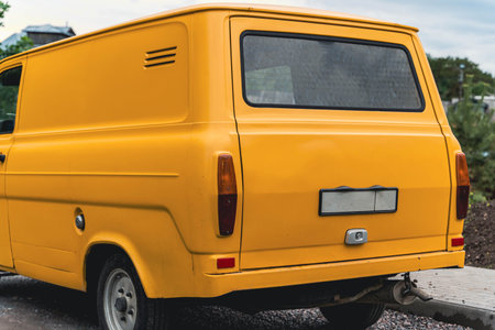 A yellow vintage van is parked on a street.