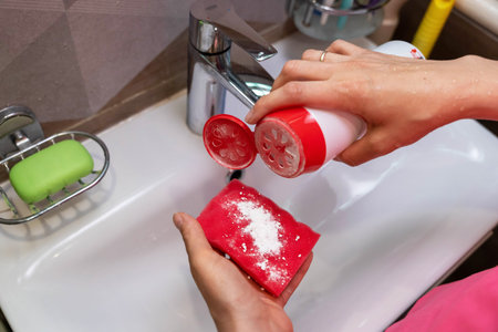 Closeup of a person pouring cleaning powder onto a spongeの写真素材