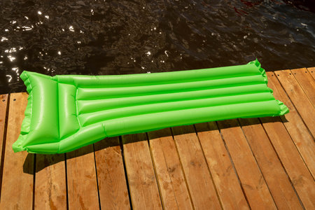 Inflatable float lies peacefully on a wooden dock by the waterの写真素材
