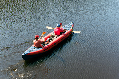 Two people paddle a kayak across calm waters under the sunの写真素材