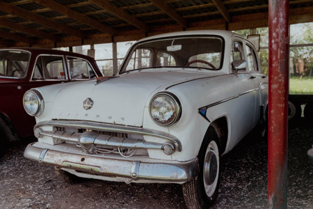 Pskov Region, Russia , July 21, 2024 - Classic car sits idle in a wooden barn among other vehicles, Moskvich 407のeditorial素材