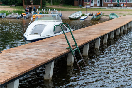 Pskov Region, Russia , July 17, 2024 - dock leading to a tranquil lake filled with parked boatsのeditorial素材