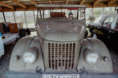 Pskov Region, Russia , July 21, 2024 - person examines an old vehicle in a dusty structure, GAZ 69のeditorial素材