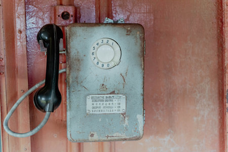 Pskov Region, Russia , July 21, 2024 - rotary telephone is fixed to a weathered wall in an old spaceのeditorial素材