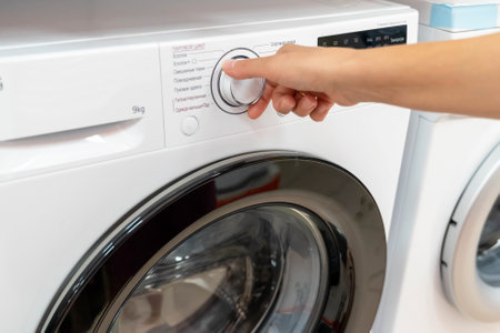 A hand reaches to select a wash cycle on the washing machine.の写真素材