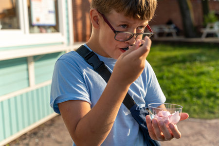 The boy takes a bite of dessert from a clear bowl in daylight. ice creamの写真素材