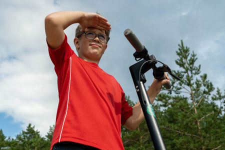 A young individual on a scooter looks ahead while enjoying the outdoors.の写真素材