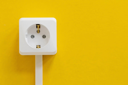 A white electrical outlet is mounted on a vibrant yellow wall.