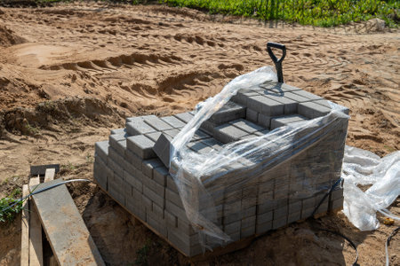 A stack of gray bricks is wrapped in plastic at a construction site.の写真素材