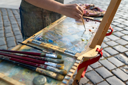 An artist engages in painting outdoors with a colorful palette and brushes.の写真素材