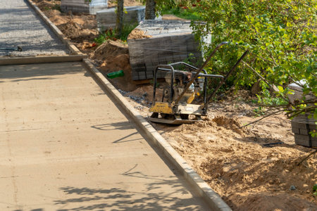 A compacting machine is working on new concrete in a garden area.の写真素材
