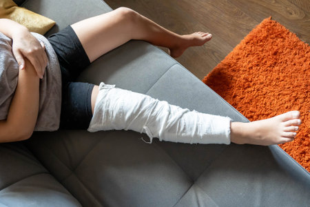 Child resting on sofa with broken leg in plaster castの写真素材